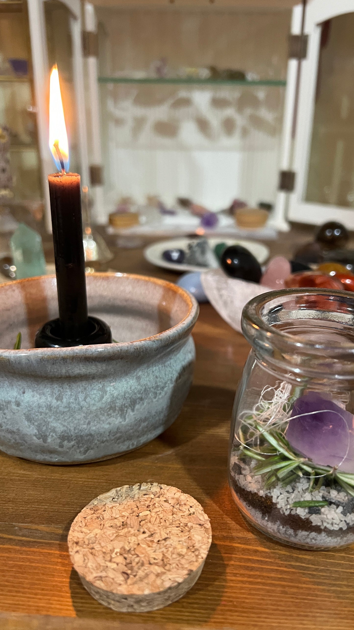 A black ritual candle burning next to a spelljar that has been recently created.