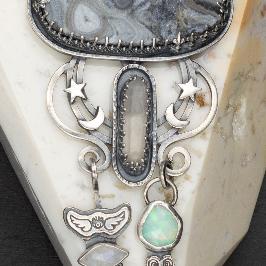 Close up of blue tara quartz, welo opal, and rainbow moonstone. All set in sterling silver with eye, wings and moon and start details.