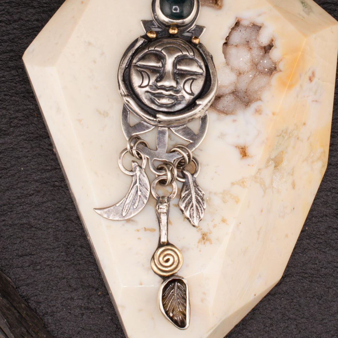 Close up details of sterling silver cast leaf, 18k gold plated spiral detail and crescent moon carved face.