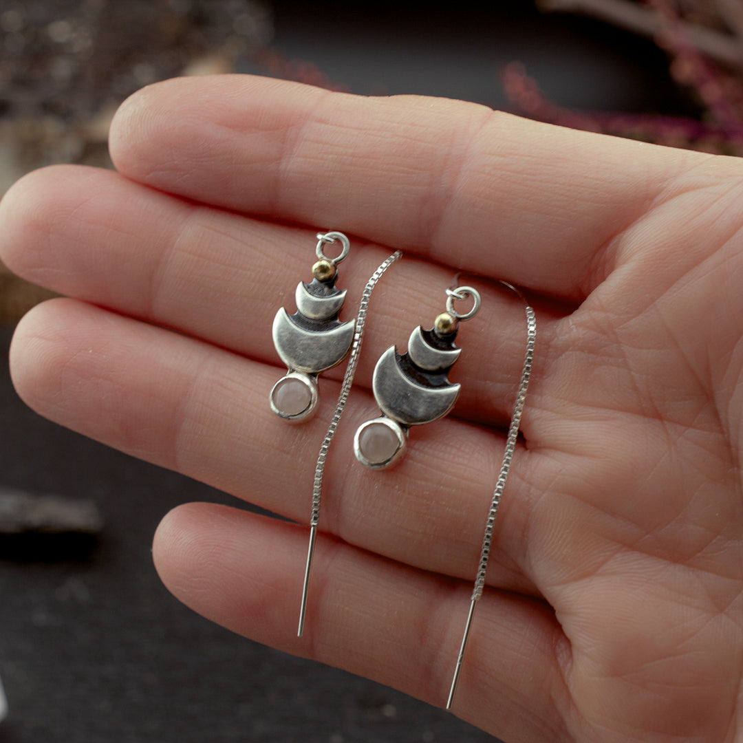 Sterling silver earrings held in a hand to show their small and dainty size.