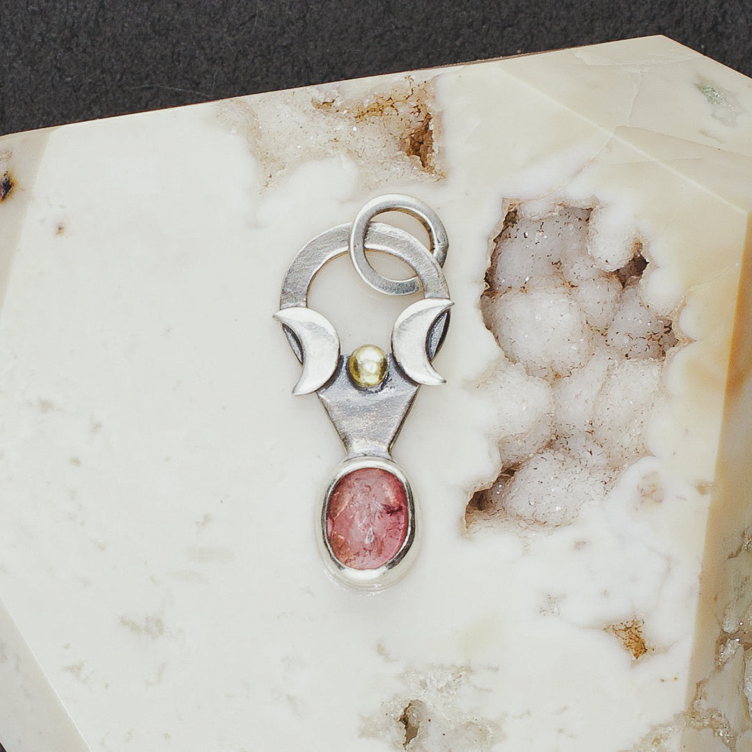 Close up of a delicate triple goddess and tourmaline witchy charm.