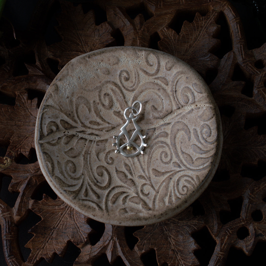 Silver sacred geometry sigil charm featuring a 22k gold plated dot with a diamond rising out of it.