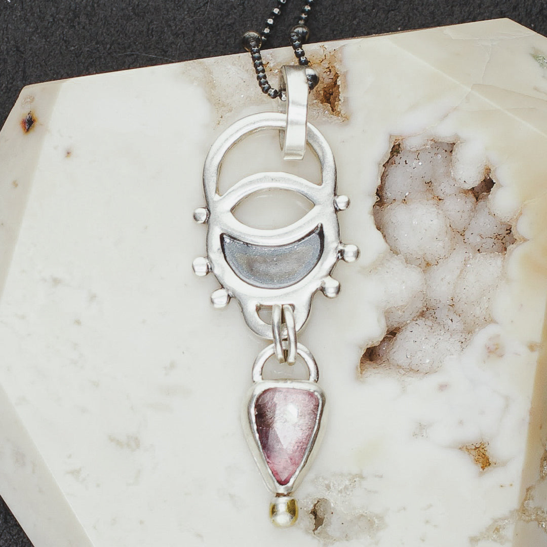 Close up of vesica piscis dainty sterling silver necklace with pink tourmaline dangle.