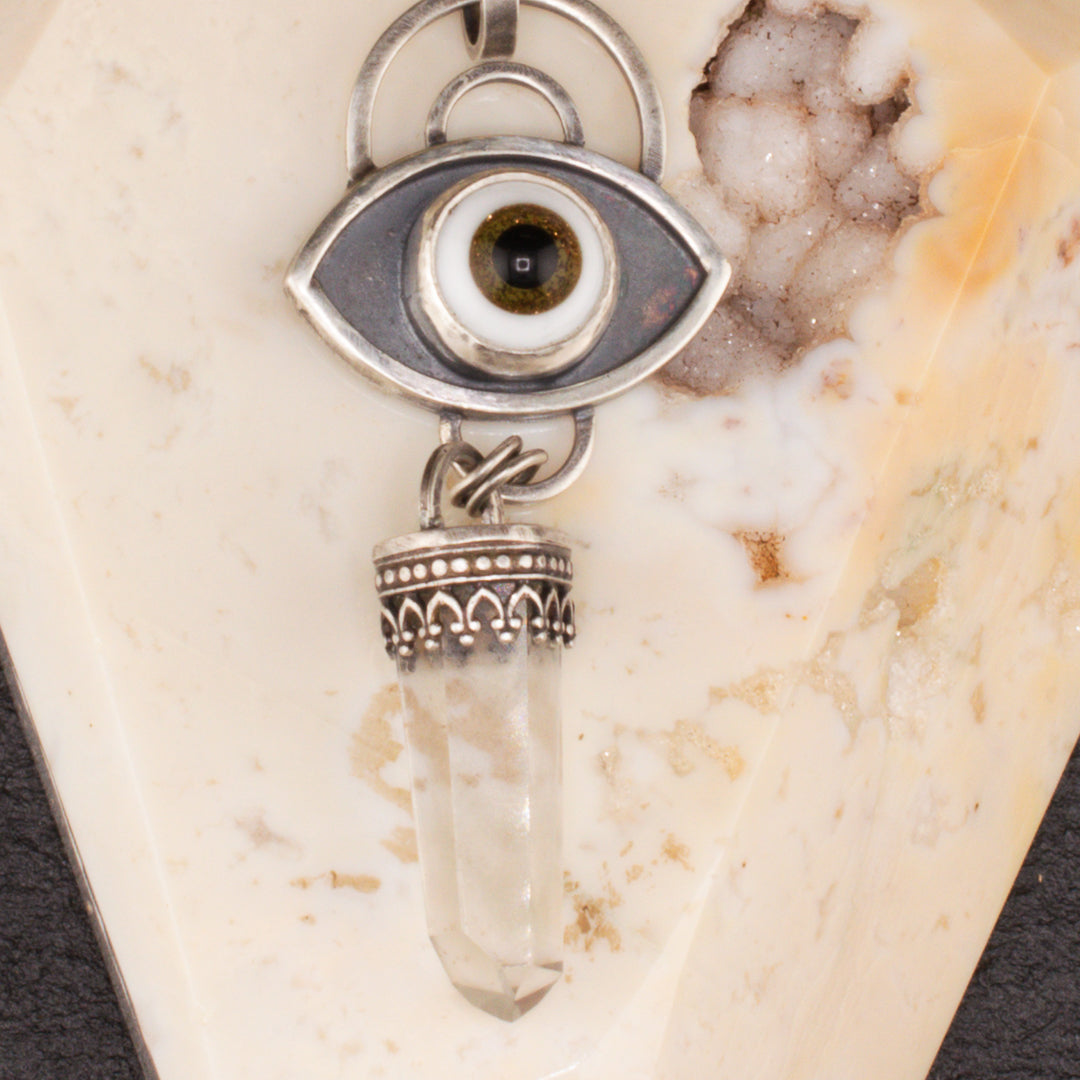 Close up of brown glass eye pendant in sterling silver with phantom quartz point.