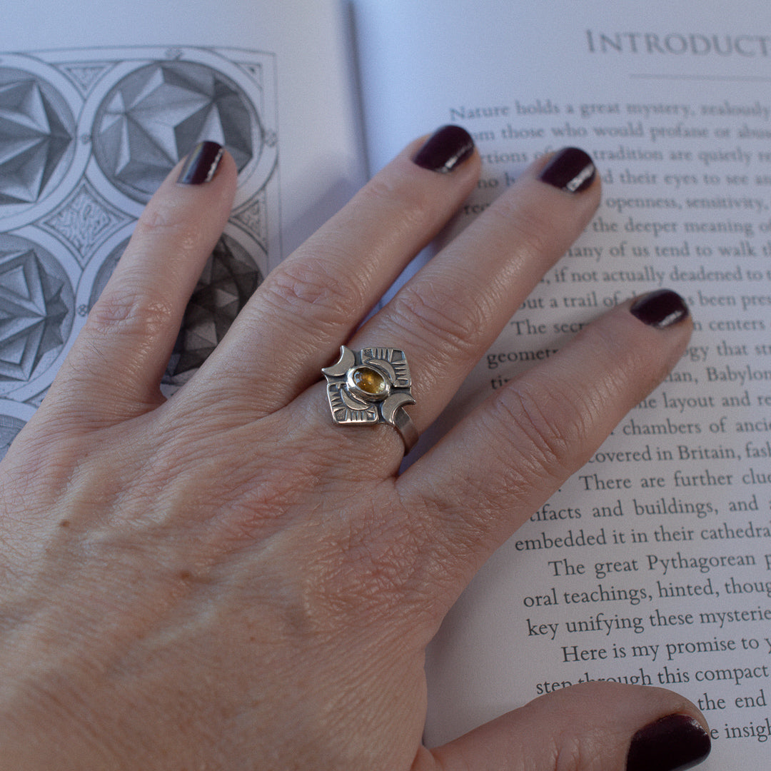 Hand with a sterling silver and crescent moon ring featuring a yellow tourmaline gemstone.