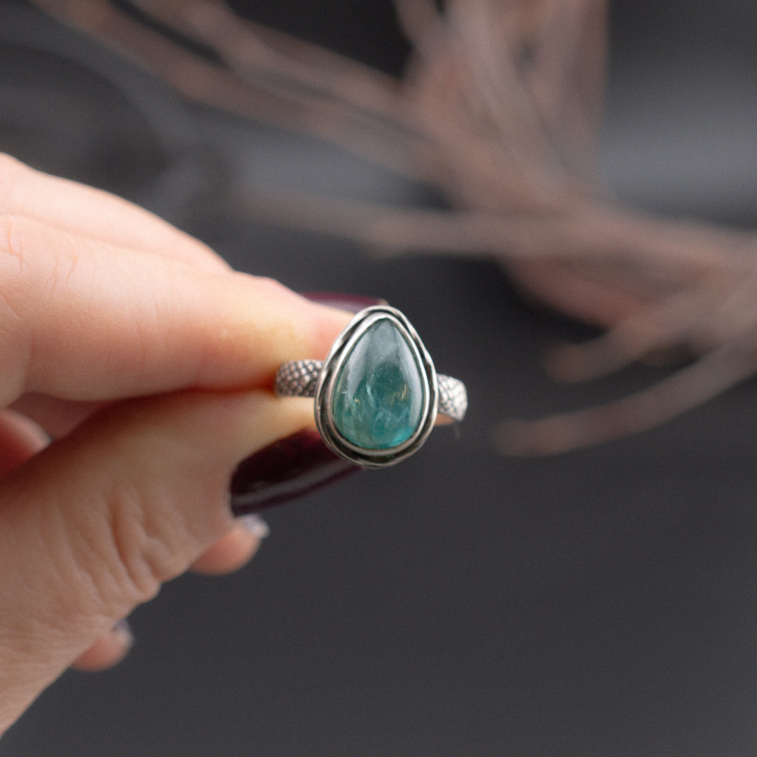 Hand presenting a turquoise kyanite tear drop shaped ring set in sterling silver.