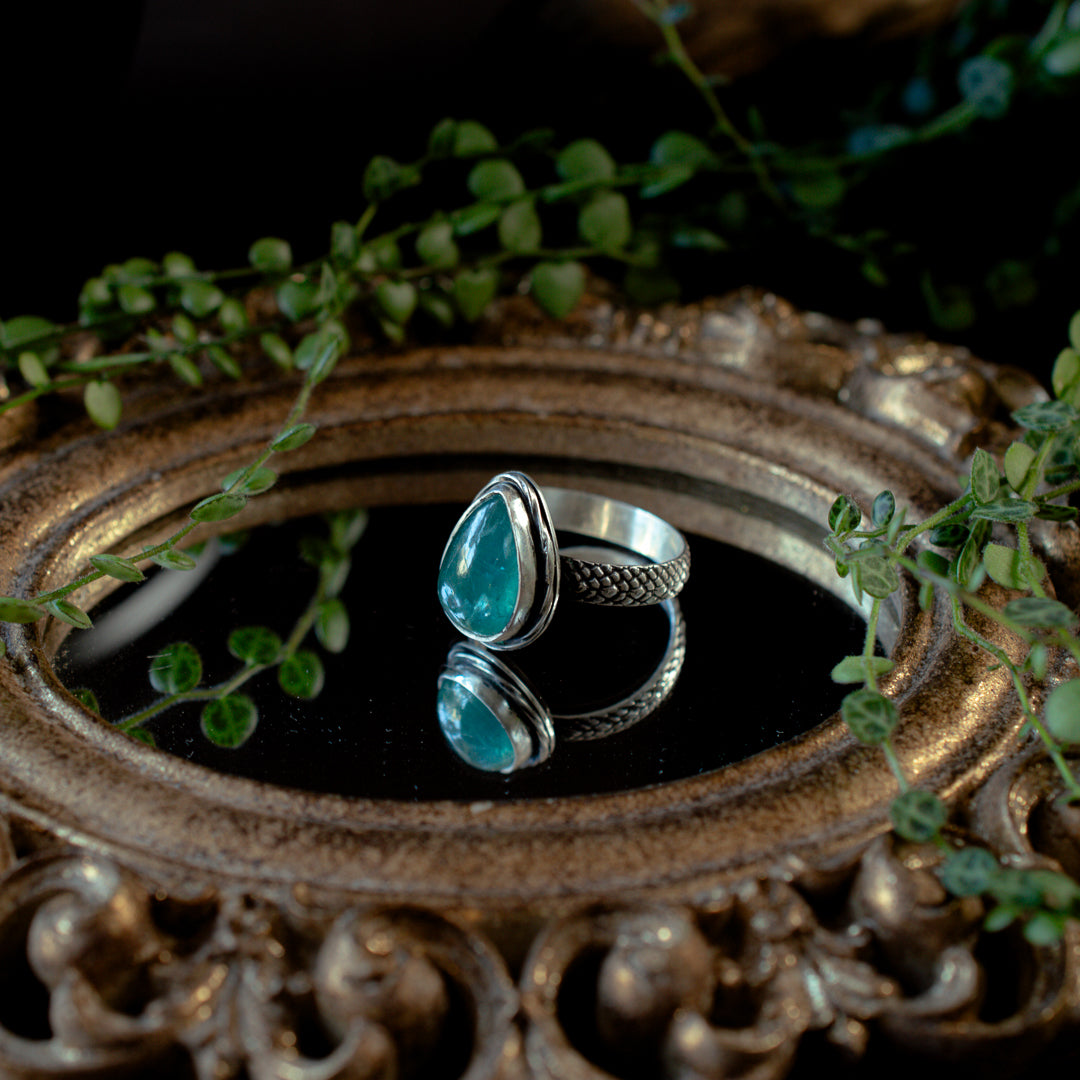An aqua kyanite cocktail ring with a sterling silver scaled textured band.