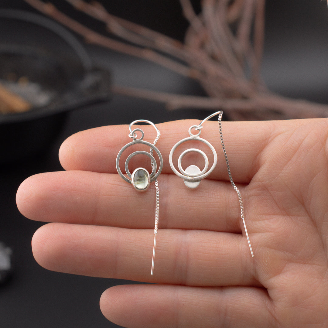 Hand showing the front and back of silver dangle earrings with grren tourmaline.