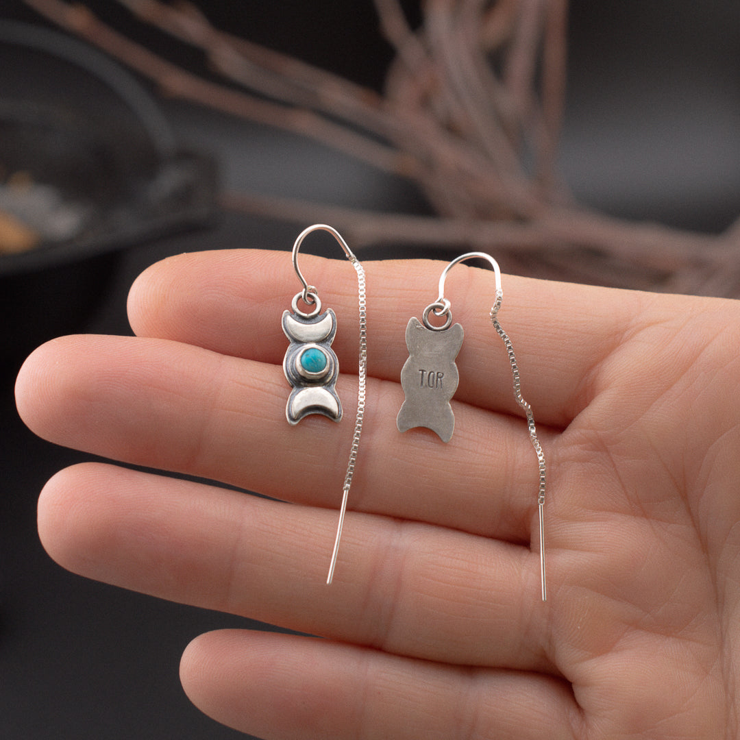 Hand holding these dainty crescent moon and turquoise sterling silver earrings.