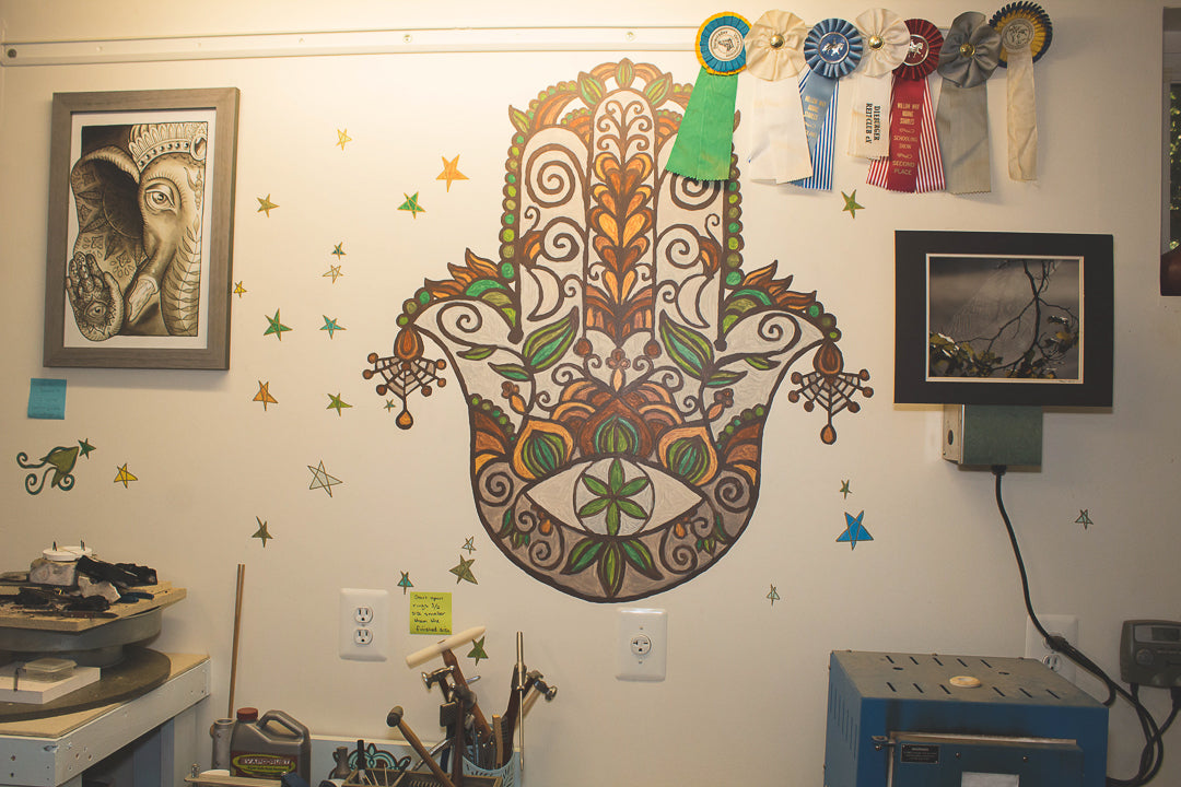 Original hamsa mural painted on a wall with leaves and spiderwebs.