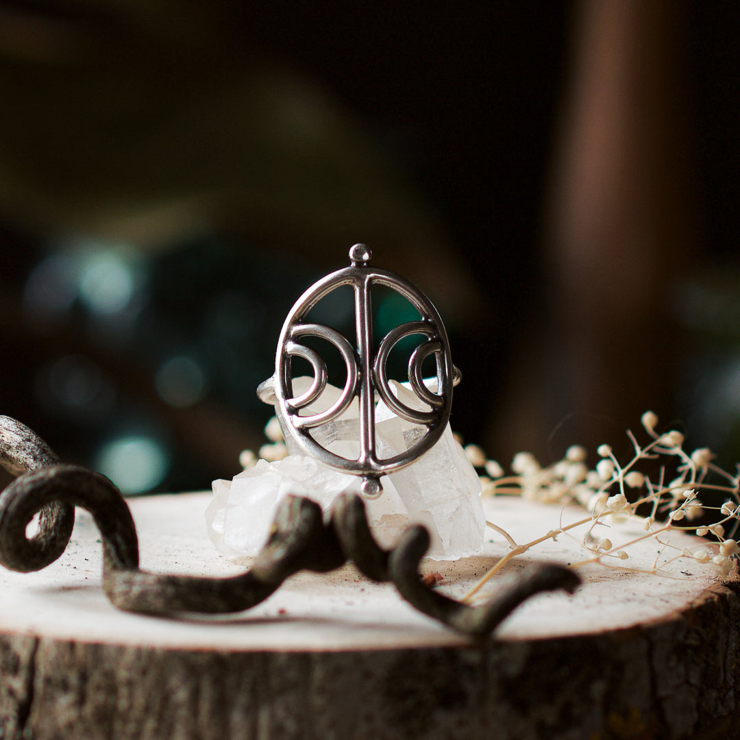 Sterling silver crescent moon ring sitting on a clear quartz crystal.