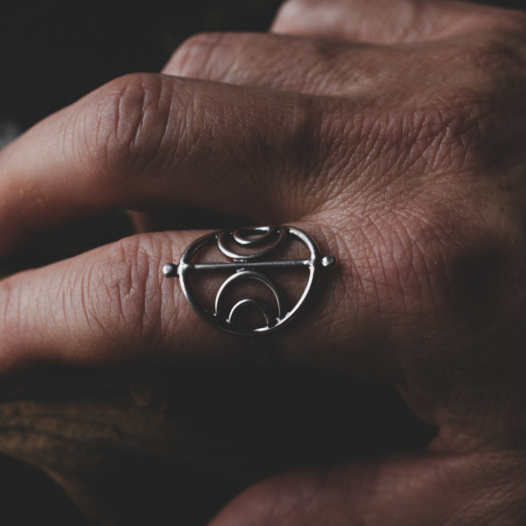 A moody picture featuring a hand with a terling silver lunar sigil ring.