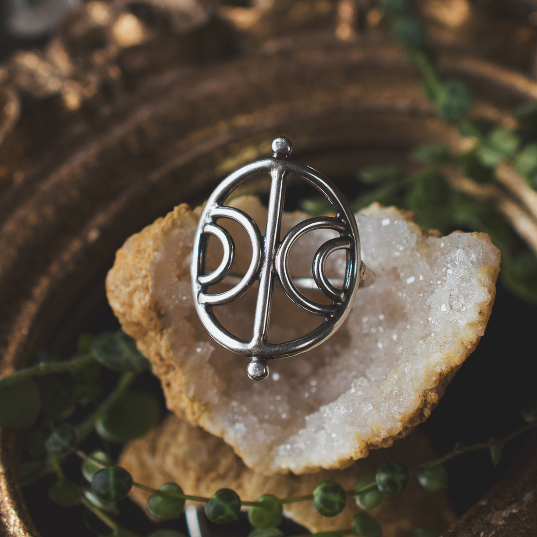 A sterling silver wire sigil ring sitting on a geode.
