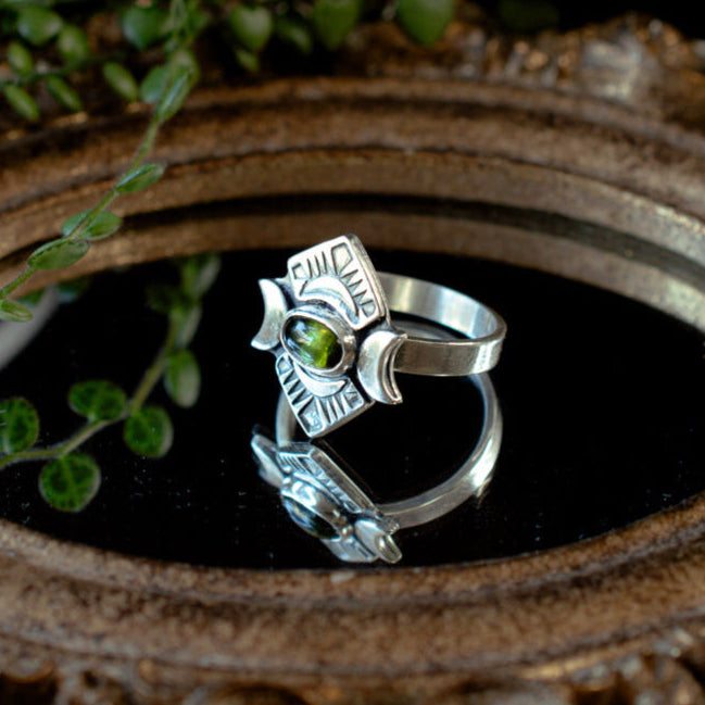 A grounding bright green tourmaline ring in sterling silver with crescent moons and stamped details.