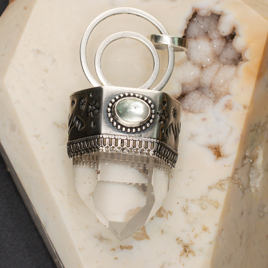 Close up of stamped sterling silver bezel with stars and mint tourmaline and a chunkl=y clear quartz point.